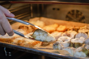 Evde balık pişirme süreci. Balık şeklinde ev yapımı pişirilmiş ürünler. Bir el balığa zeytinyağı sürer. Yüksek kalite fotoğraf