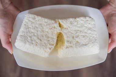 Bir el bir parça süzme peyniri yakından tutar. Lezzetli ve sağlıklı yiyecekler yemek. Yüksek kalite fotoğraf