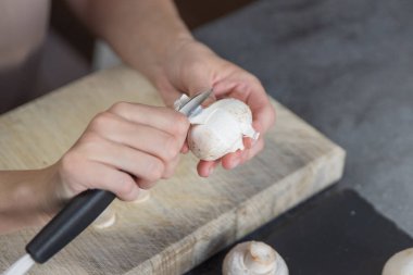 Mantar soyma işlemi. Bir kadının elleri mantarları bıçakla soyar, yakın plan. Mantar pişiriyorum. Yüksek kalite fotoğraf