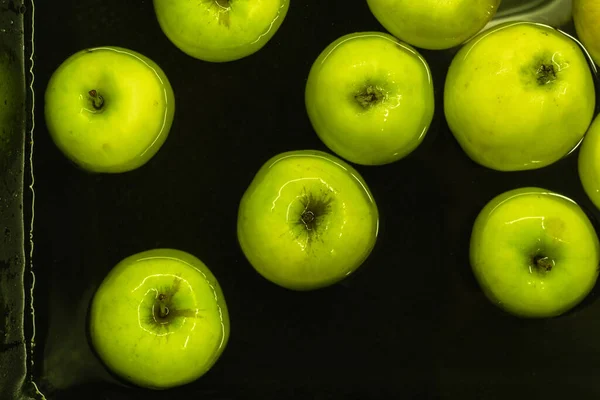 Flat lay of green ripe apples floating in the water. Washing fruits from the ochard
