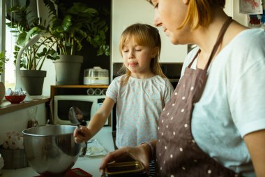Mutlu anne ve kız modern mutfakta birlikte vakit geçiriyorlar. Annem küçük, sevimli, preakademik kıza yemek pişirmeyi öğretiyor. Evde hamur işi yapıyorum.