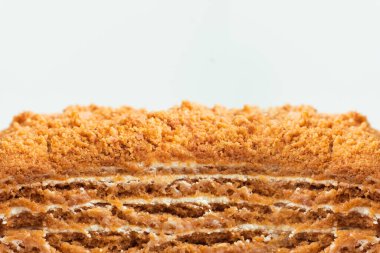 Beyaz arka planda geleneksel ballı pasta. Katmanlı kek dilimini bal bazlı ve beyaz ekşi kremayla kapat. Pastanın dokulu arkaplan olarak kesilmiş makro görüntüsü