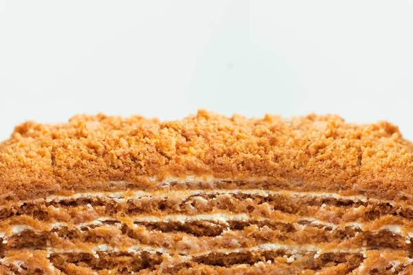 Traditional honey cake on white background. Close up of layered cake slice with honey base and white sour cream filling. Macro shot of cake cut as a textured background