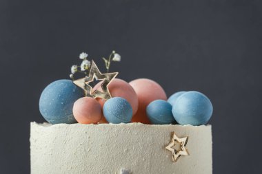 Mavi ve pembe çikolata küreleriyle süslenmiş beyaz krem peynirli bebek partisi pastası. Gelecek çocuğun cinsiyetini tahmin et. Kek ister erkek ister kadın. Doğmamış bebeğin cinsiyetini göster.