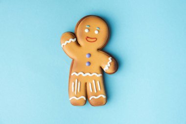 Beyaz kremayla süslenmiş zencefilli kurabiye adam mavi pastel arka planda izole edilmiş. Düz yatıyordu. Geleneksel ev yapımı Noel kurabiyeleri. Boşluğu kopyala