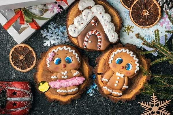 Christmas gingerbread house shaped cookie with white snow icing and gingerbread men on the winter festive background. Homemade traditional cookies. Gingerbread couple. Flat lay