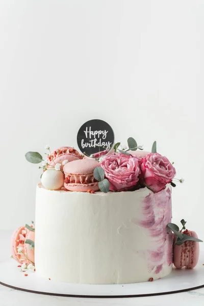 白い背景に赤いバラとピンクのマカロンで飾られた白いクリームチーズの霜が付いている誕生日ケーキ 誕生日おめでとうございます — ストック写真