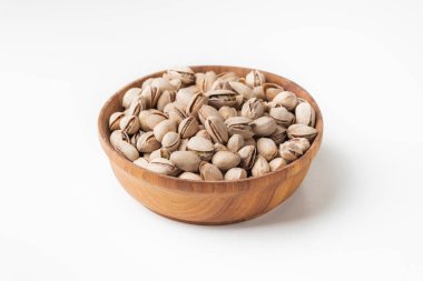 Pistachio fındık tohumlarını beyaz arka plandaki ahşap bir kaseye koy. Kabuklu şam fıstığı. Kurutulmuş tuzlu bira.