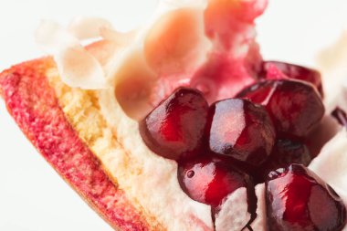 Beyaz arka planda olgun nar meyvesi fincanı. Olgun nar, kırmızı sulu tohumlarla ikiye bölünmüş. Yakın plan.