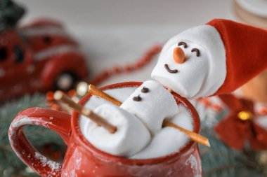 Marshmallow Kardan Adam süt köpüklü kakao dolu kırmızı seramik bir bardakta jakuziye giriyor. Noel tatili planı. Kış konsepti. Marşmelovlu ve şenlikli sıcak çikolata..