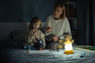 Anne ve küçük kızı elektrik kesintisi sırasında karanlıkta çalışıyor ve resim çiziyorlar. Küçük kız bilinç kaybı sırasında ev ödevini yapmak için kamp feneri kullanıyor. Enerji krizi kavramı