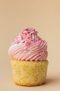 Vanilyalı kek ve pembe kremalı krema kapağı. Kek üzerine krem peynir süslemesi. Küçük pembe kalp şeklinde çikolata sosuyla süslenmiş. Bej arka plan. Sevgililer Günün kutlu olsun.