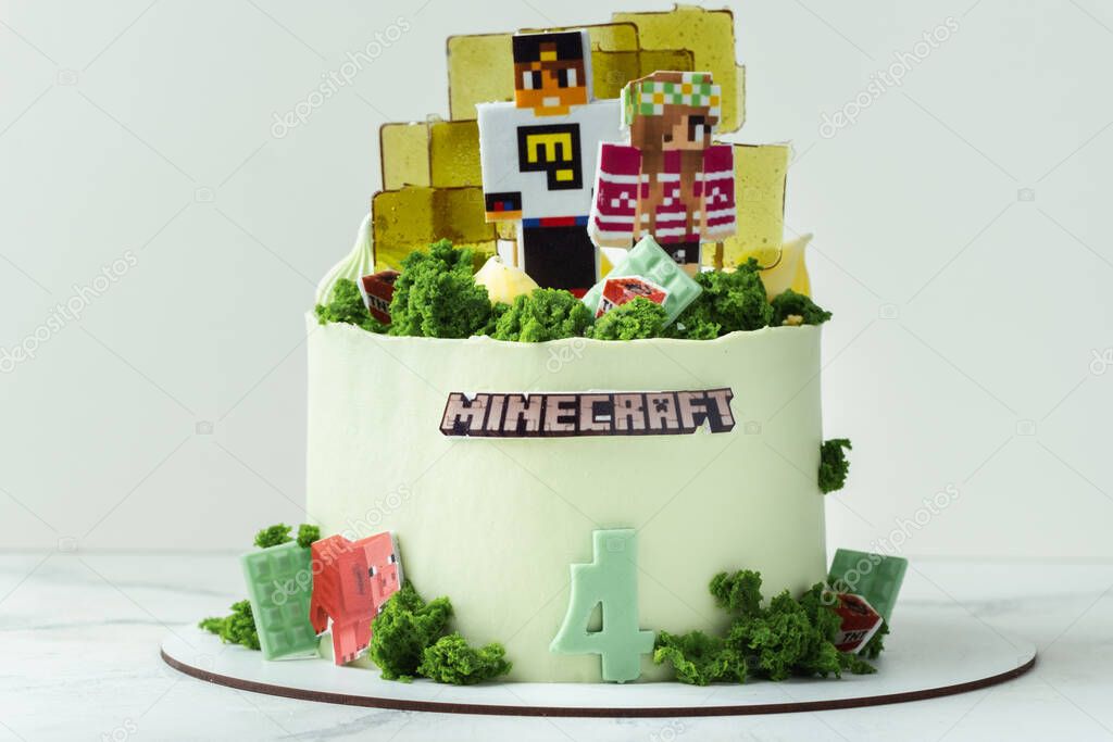 KYIV, UKRAINE - December 11: Birthday cake for a fan of Minecraft game on white background. Cake for a gameboy decorated with edible green grass and square caramel candies