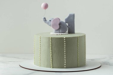 Bir yaşındaki bir bebek için doğum günü pastası. Bebek partisi pastası. Gri arkaplanda fil şekilli mastik figürle süslenmiş pastalı pastası olan küçük bir çocuk için doğum günü pastası.