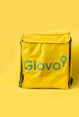KYIV, UKRAINE - January 17: Glovo thermal yellow food bag isolated on yellow background. Mockup for food delivery company. Ordering food concept. Copy space for a free text.