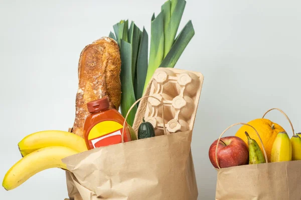 Food products from the grocery shop. Food shopping and delivery concept. Bread, eggs, bananas, fruits and vegetables in the brown paper shopping bag. Healthy nutrition concept