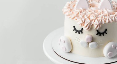 Cat cake for a little girl decorated with edible eyelids, ears and mastic paws on the white background. Birthday cake with white and pink cream cheese frosting