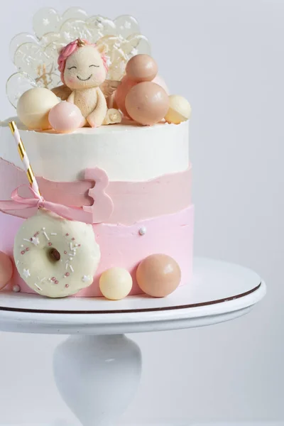 女の子のための誕生日ケーキピンクのパステルクリームチーズの霜が白い背景にユニコーンフィギュア チョコレート球とキャラメルキャンディーで飾られています — ストック写真