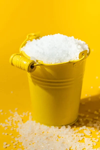 粗糙的白盐在一个黄色金属小桶中的黄色背景 文件的自由篇幅 — 图库照片