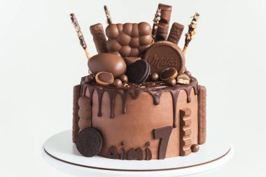 KYIV, UKRAINE - 3 Mart: üzerinde kahverengi krem peynirli pasta ve Milka şekerleri, Oreo kurabiyeleri ve çikolatalı yumurta bulunan siyah çikolata damlaları. Beyaz arkaplan