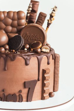 KYIV, UKRAINE - 3 Mart: üzerinde kahverengi krem peynirli pasta ve Milka şekerleri, Oreo kurabiyeleri ve çikolatalı yumurta bulunan siyah çikolata damlaları. Beyaz arkaplan