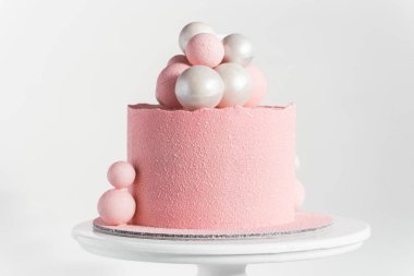 Beyaz arka planda gümüş ve pembe çikolata küreleriyle süslenmiş pembe kadife kaplı doğum günü pastası.