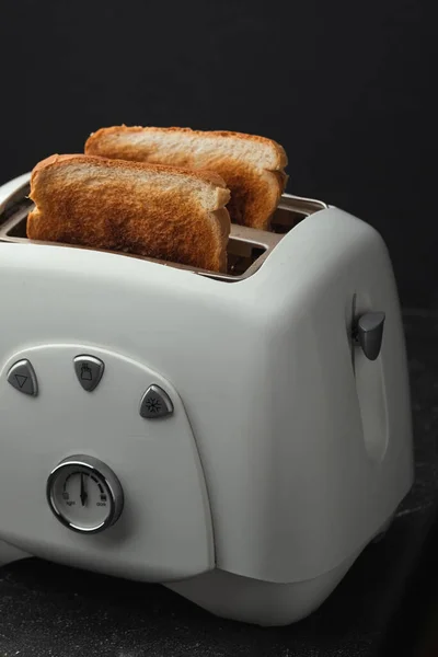 在黑色背景上 从烤面包机上伸出的少许烧焦的白面包烤面包的特写镜头 准备好了 用深色的外壳烤面包 早上早餐的概念 — 图库照片