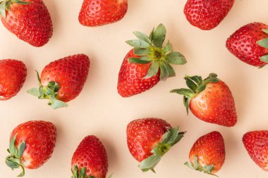 Bej arka planda taze olgun kırmızı çileklerin üst görüntüsü. Yaz meyveleri dokulu arka plan. Düz yatıyordu