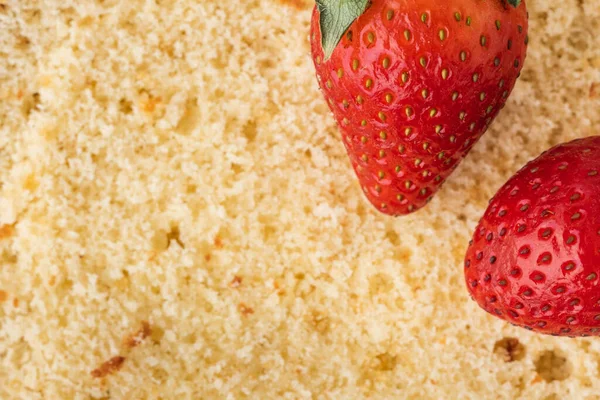 Yellow vanilla sponge biscuit cake texture. Macro shot. Pastry dough textured background with red strawberries. Top view
