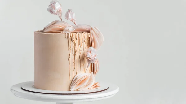 白を背景に砂糖の花や食用紙の装飾で飾られたベージュチョコレートアイシングと美しい大きなケーキ — ストック写真