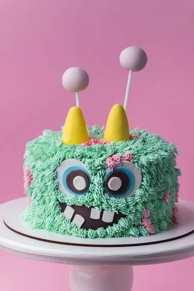 粉色背景上的怪兽主题蛋糕 有趣的生日蛋糕与绿松石蓬松奶油奶酪糖霜 可怕的怪物糕点与可食用的毛皮 万圣节快乐派对 — 图库照片