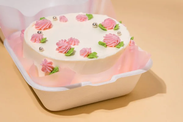 在米色背景的白色礼品盒中 装饰着粉红乳酪花的韩国风格的小本托蛋糕 蛋糕是送给心爱的人的礼物一个女人的春嫩蛋糕 顶部视图 — 图库照片