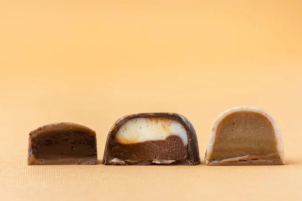 一套自制的褐色巧克力薄片 手绘糖果的配售 凯蒂把它切成两半 带复制空间的调校 米色背景的巧克力制品宏观图片 — 图库照片