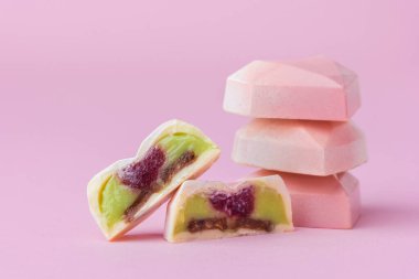 Ev yapımı pembe kalp şeklinde çikolata bonbonları. Elle boyanmış şekerler. İkiye bölünmüş şeker. Fotokopi alanı olan bir model. Pembe arka planda çikolatalı ürünlerin makro çekimi