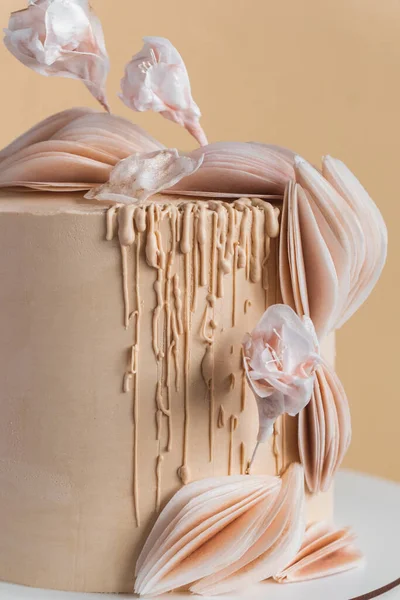 ベージュのチョコレートアイシングと美しい大きなケーキは 食用砂糖の花で飾られ ベージュの背景に食用紙の装飾 — ストック写真