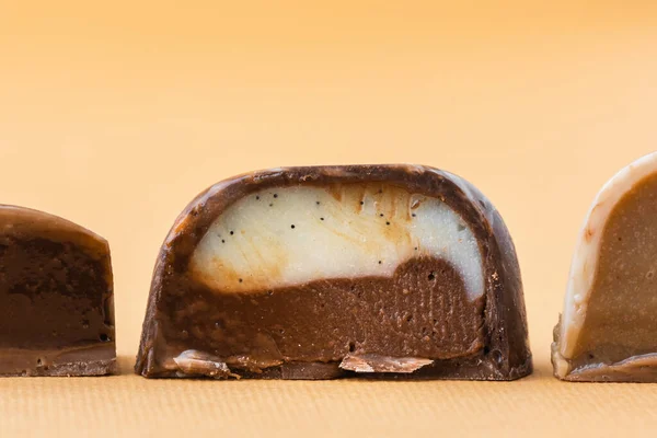 一套自制的褐色巧克力薄片 手绘糖果的配售 凯蒂把它切成两半 带复制空间的调校 米色背景的巧克力制品宏观图片 — 图库照片