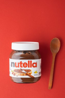 KYIV, UKRAINE - 21 Şubat: Nutella çikolatalı fındık, cam bir kavanoza serpilmiş, yanında beyaz kaşık ve kırmızı fındık var. Üst Manzara. Boşluğu kopyala.