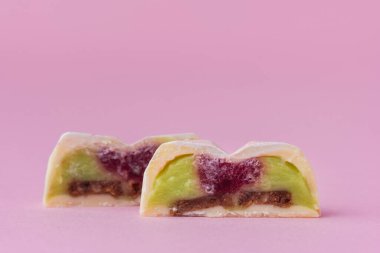 Ev yapımı pembe kalp şeklinde çikolata bonbonları. Elle boyanmış şekerler. İkiye bölünmüş şeker. Fotokopi alanı olan bir model. Pembe arka planda çikolatalı ürünlerin makro çekimi