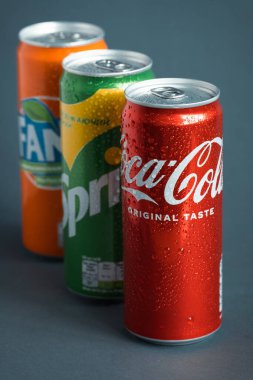 KYIV, UKRAINE - 09 Mayıs - Gri arkaplanda klasik Coca-Cola, Sprite ve Fanta kutularının yakın çekimi. Coca-Cola şirketinin popüler ürünleri. Soğuk içecek konsepti