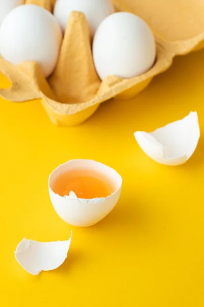 stock image Close up of white eggs in the carton brown box on the yellow background. Macro shot of broken egg with white shell. Copy space for a free text.