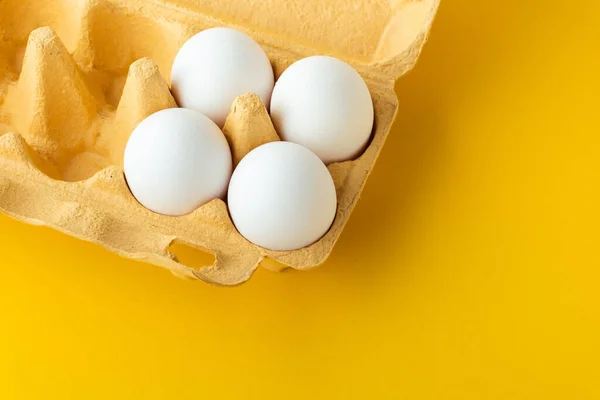 stock image Close up shot of white eggs in the carton brown box on the yellow background. Macro shot. Copy space for a free text.