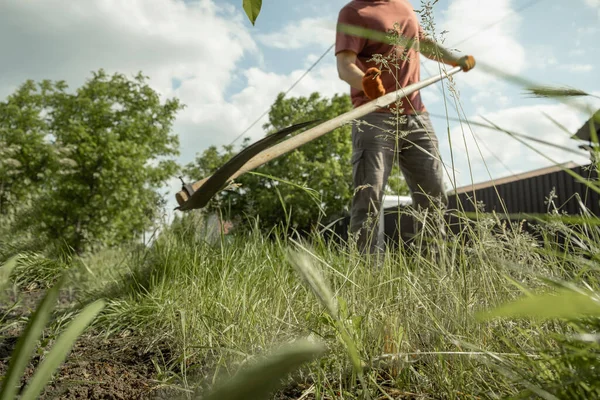 stock image Farmer mowing the grass with classic scythe during hot summer day. Traditional way of mowing the grass on a farmland