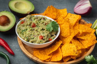 Beyaz kase, gri beton arka planda nachos ile geleneksel Meksika guacamolesi. Avokado, kişniş, soğan, acı biber ve limon karışımı soslu tortilla cipsi.
