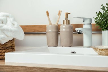 Modern ev banyosu iç mimarisi. Yeşil bitkili beyaz lavabo ve musluk, temiz havlular ve banyo aksesuarları