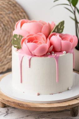 Tahta pasta standında pembe çikolata çiçekleriyle süslenmiş beyaz krem peynirli doğum günü pastası. Bir kadın için yıldönümü pastası