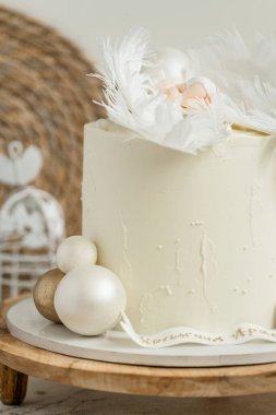 Yenilebilir melek kanatlarında uyuyan mastik yeni doğmuş bebekle süslenmiş beyaz krem peynirli vaftizli pasta. Küçük bebek melek uyuyor. Bebek doğumu kutlaması.