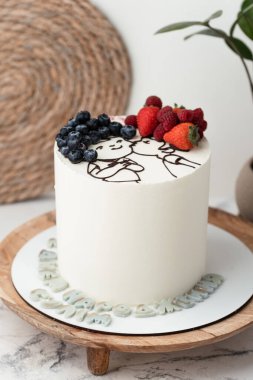 Yaban mersini ve çilekle süslenmiş bir oğlanı öpen beyaz çikolata kremalı yıldönümü pastası. Sevgililer Günü için konsept pasta