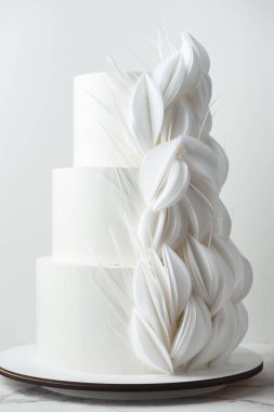 Yenilebilir gofret kağıdından yapılmış çiçeklerle süslenmiş beyaz çikolatalı büyük bir düğün pastası. Beyaz arkaplan