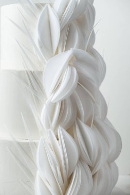 Yenilebilir gofret kağıdından yapılmış çiçeklerle süslenmiş beyaz çikolatalı büyük bir düğün pastası. Beyaz arkaplan