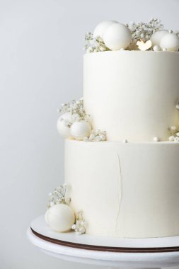 Beyaz çikolata kaplı büyük ranza düğün pastası ve beyaz arka planda beyaz çikolata küreleri ile süslenmiş..